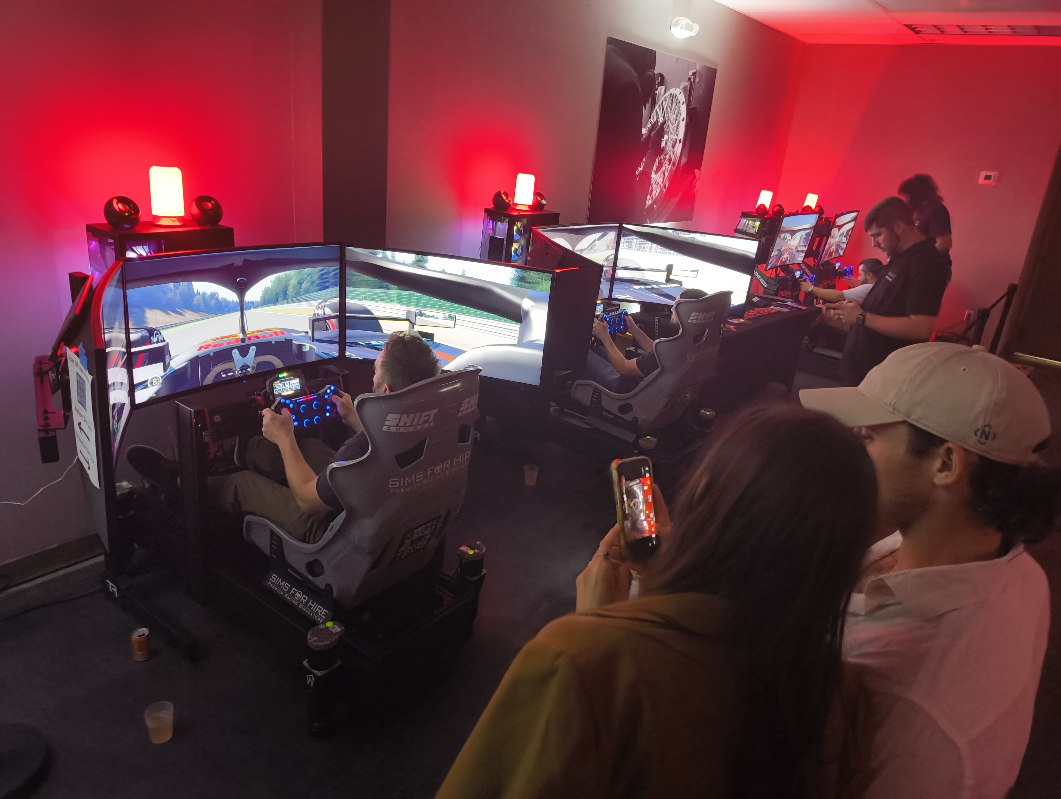 Driver competing on racing simulator with exotic cars in background